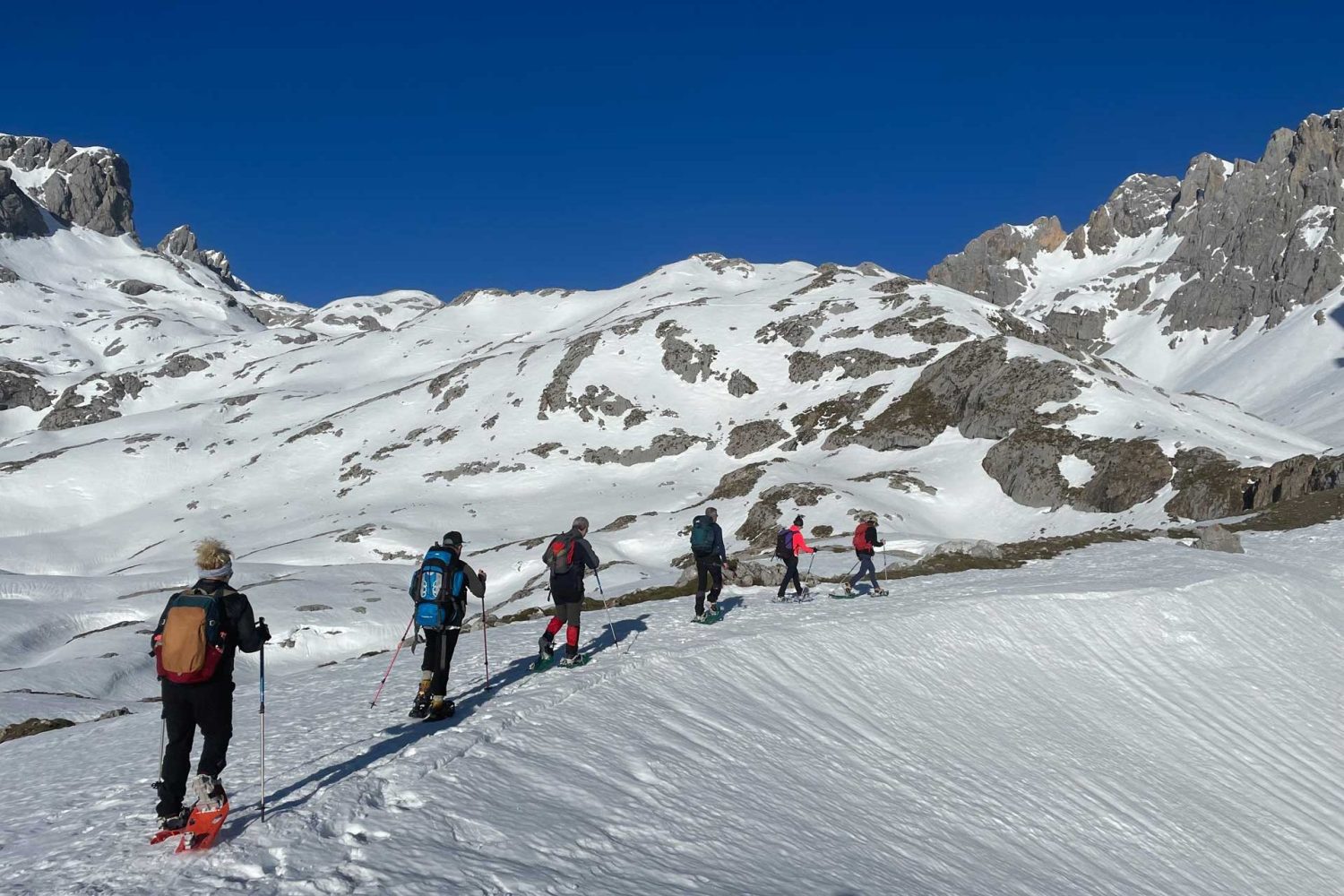 Seis personas subiendo por una pista de nieve con raquetas de nieve - fotopicos.com