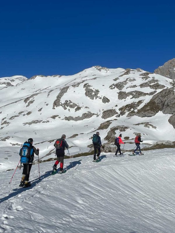 Seis personas subiendo por una pista de nieve con raquetas de nieve - fotopicos.com