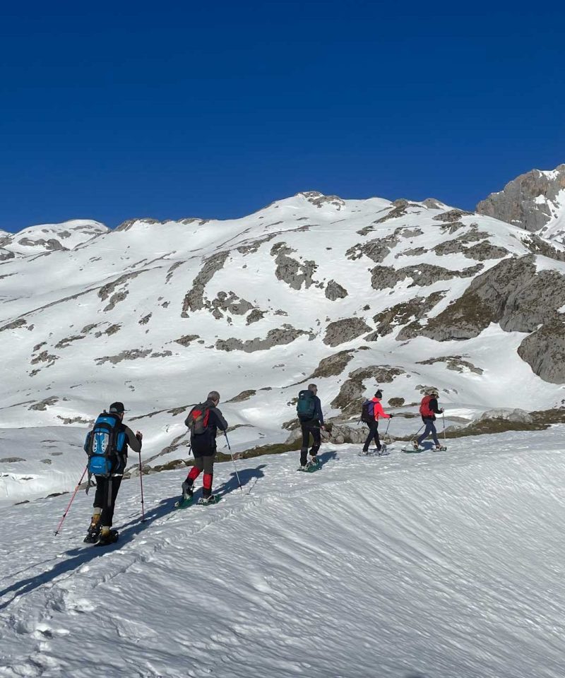 Seis personas subiendo por una pista de nieve con raquetas de nieve - fotopicos.com